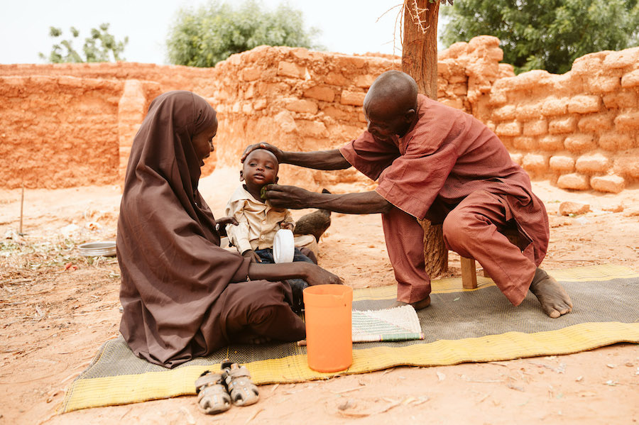 Hauwa sentada en su casa junto a su marido, Yahaya Mati, y su hijo, Hamza
